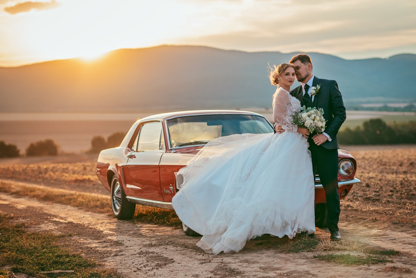 Romantický svadobný portrét novomanželov pri červenom veteráne počas západu slnka od fotografky Silvie Pavlíkovej.