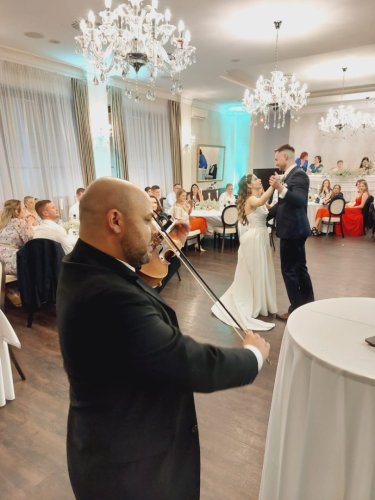 Huslista v obleku hrá na svadobnej hostine počas prvého tanca novomanželov v štýle Bridgerton Violin Experience.