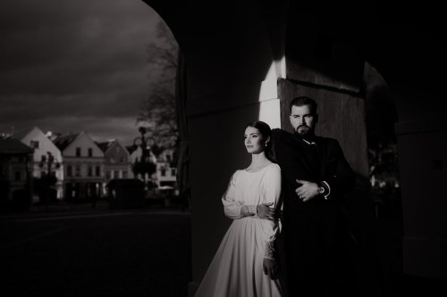 Umelecký čiernobiely svadobný portrét nevesty a ženícha v historickom podloubí od fotografa Adriána Juríčka.