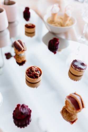 Elegantný výber slaných predjedál a chuťoviek od Empresa catering & events podávaný na zrkadlovom podnose.