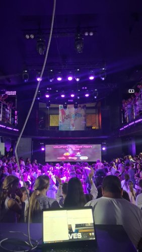 Pohľad z réžie na zaplnený klub počas kultúrnej akcie s fialovým osvetlením a pódiom pre Lollipopz.