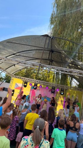 Deti a mládež sledujú vystúpenie na pódiu počas kultúrnej akcie pod holým nebom.