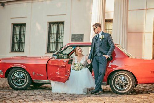Romantický svadobný portrét nevesty a ženícha pri červenom veteráne Ford Mustang od fotografky Silvie Pavlíkovej.