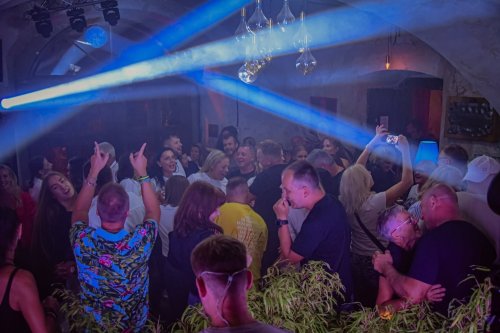 Zabávajúci sa hostia na tanečnom parkete počas svadobnej oslavy s DJ Marekom Búrym pod modrými svetelnými lúčmi.