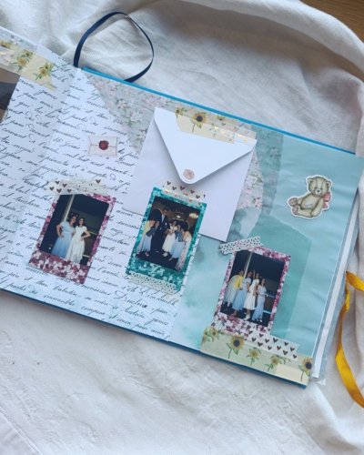 Ručne vyrobený svadobný album v štýle scrapbooking s nalepenými fotografiami, obálkou a ozdobnými nálepkami.