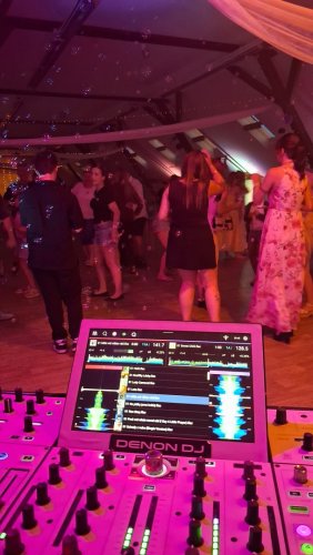 Pohľad z pozície DJ-a na tancujúcich hostí počas svadobnej oslavy s bublinkovým efektom.