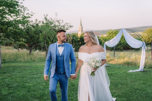 Svadobný portrét nevesty a ženícha kráčajúcich ruka v ruke v záhrade, zachytený svadobnou fotografkou Janou Cafourkovou.