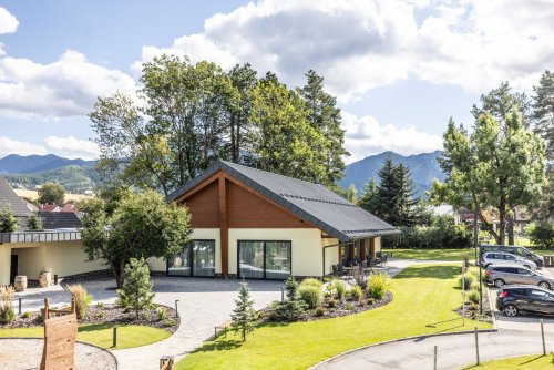 Exteriér moderného objektu Humno Demänová - event house s upravenou záhradou a výhľadom na hory.